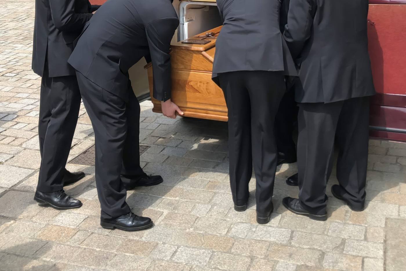 Pallbearers carrying a casket to a hearse